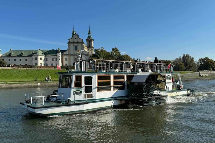 The side-wheel ship "Legenda" gracefully floating on the river, set against the backdrop of the Church on the Rock in Krakow. The historical paddle boat.