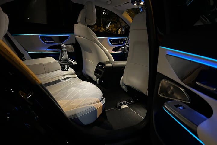 Elegant Mercedes E-Class cabin illuminated by ambient night lighting. The interior offers first-class comfort with reclining seats, refined details, and a serene atmosphere for your journey.